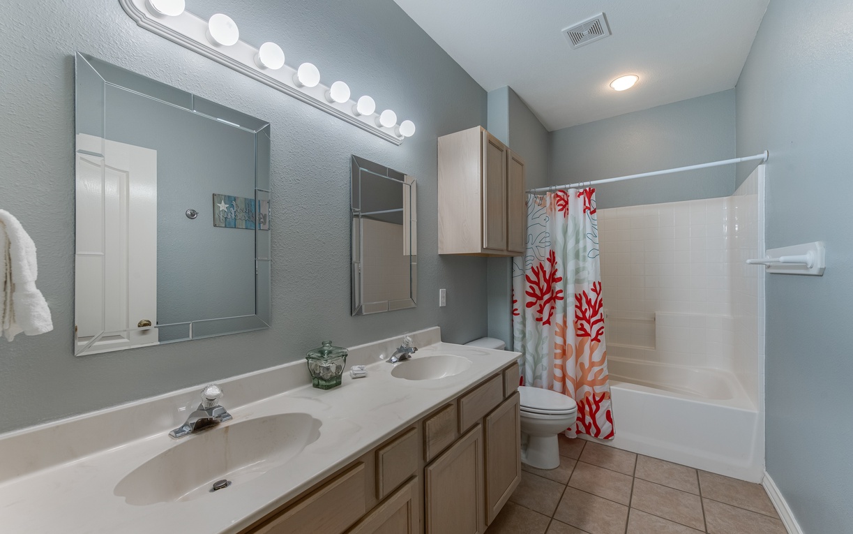 Your spacious bathroom features dual sinks, a relaxing tub-shower combo, and cheerful coral-themed décor to brighten your morning routine.