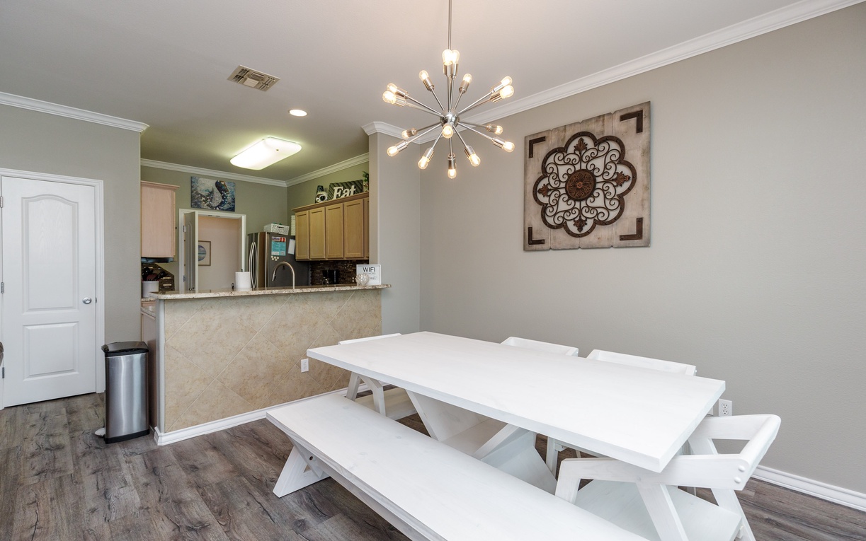 Gather around your stylish white dining table under a stunning starburst chandelier, with the open kitchen creating perfect flow for cooking and conversation.