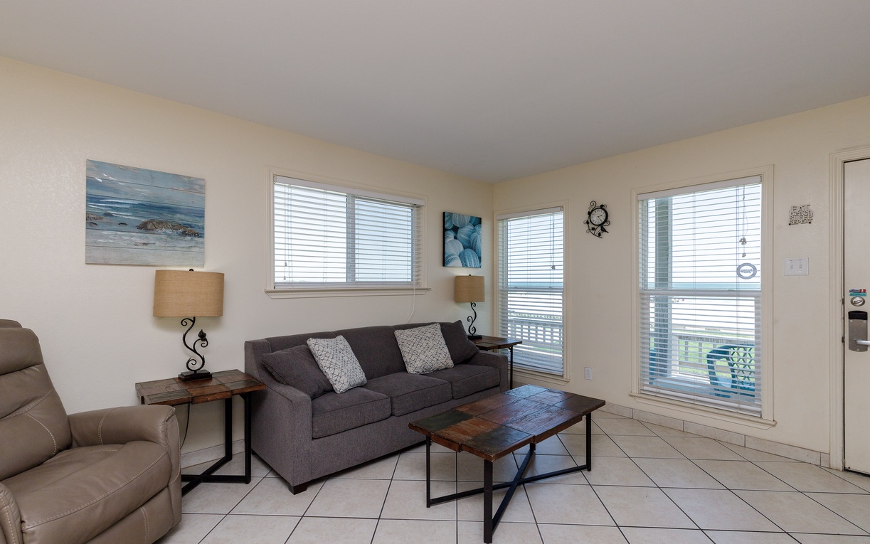 Relax in your bright living room with comfortable seating, coastal artwork, and windows that flood the space with natural light.