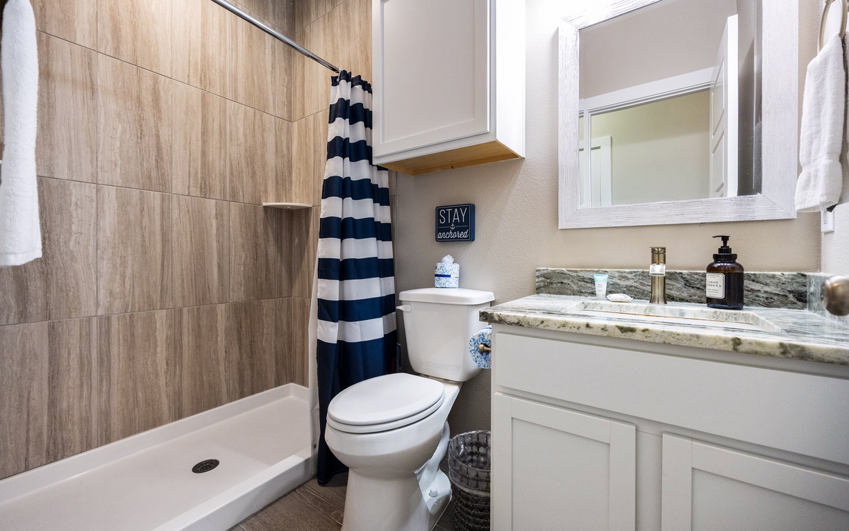 Refresh in your stylish bathroom featuring a spacious shower, granite countertops, and thoughtful amenities for your comfort.