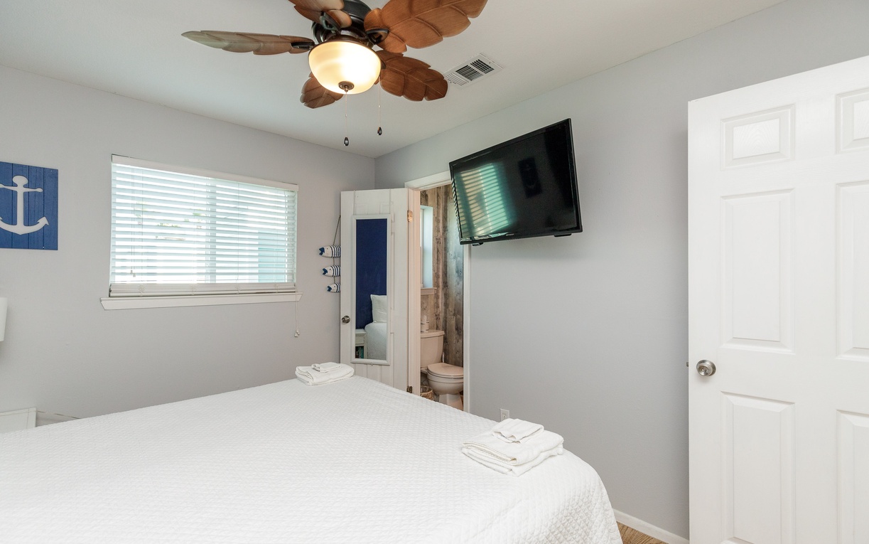 Relax in your primary bedroom with crisp king linens, ceiling fan, and wall-mounted TV for cozy evenings.