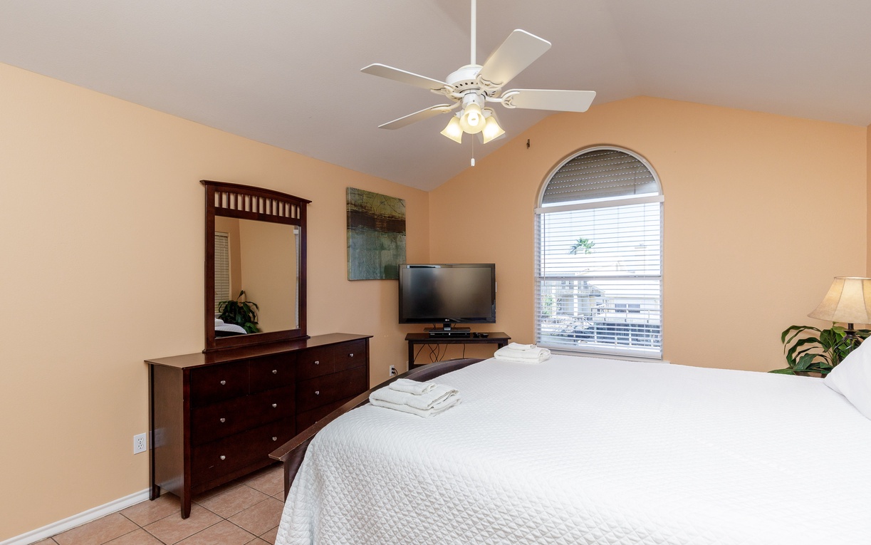 Unwind in your peaceful bedroom with comfortable furnishings, ceiling fan, and TV for cozy evenings in.