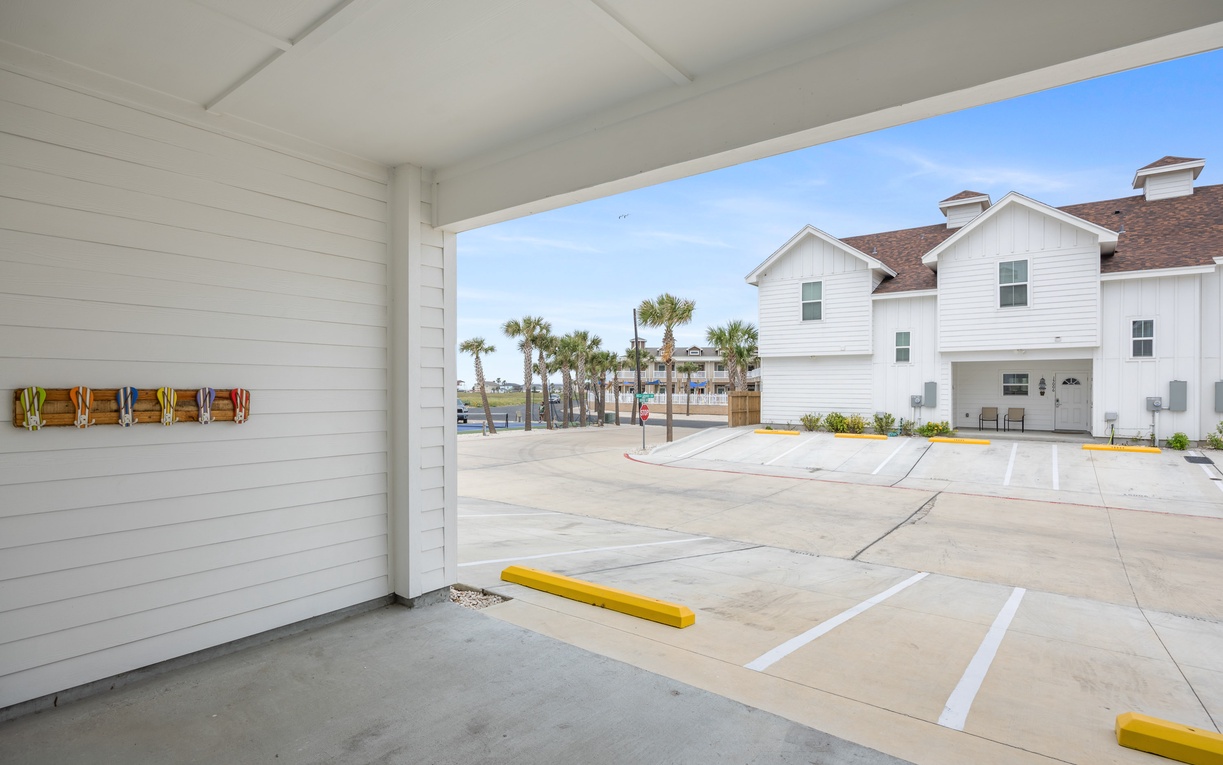 Covered parking provides shade while tropical palms and waterfront access create your perfect beach getaway backdrop.