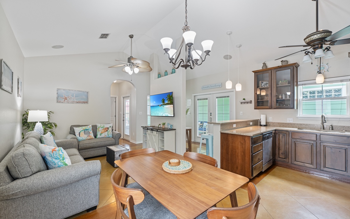Relax in your open-concept living space where coastal charm meets modern comfort, complete with full kitchen and dining area.