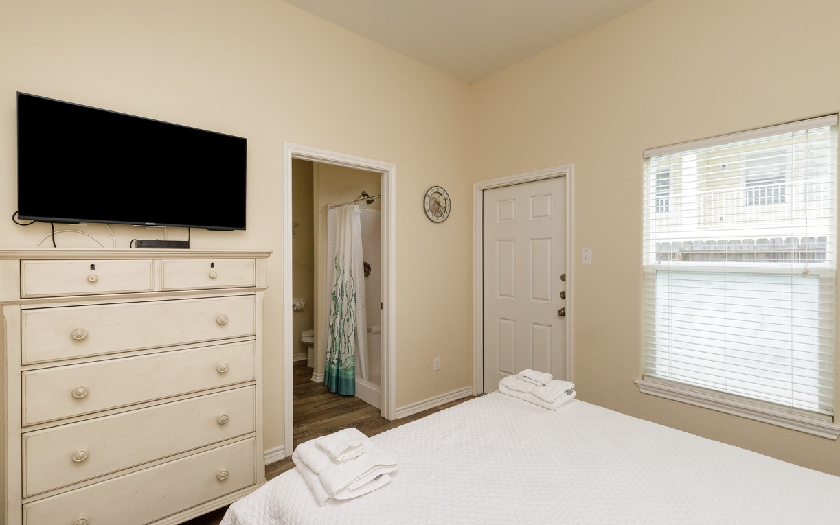First floor primary bedroom with a queen bed, private bathroom with walk-in shower and patio access.