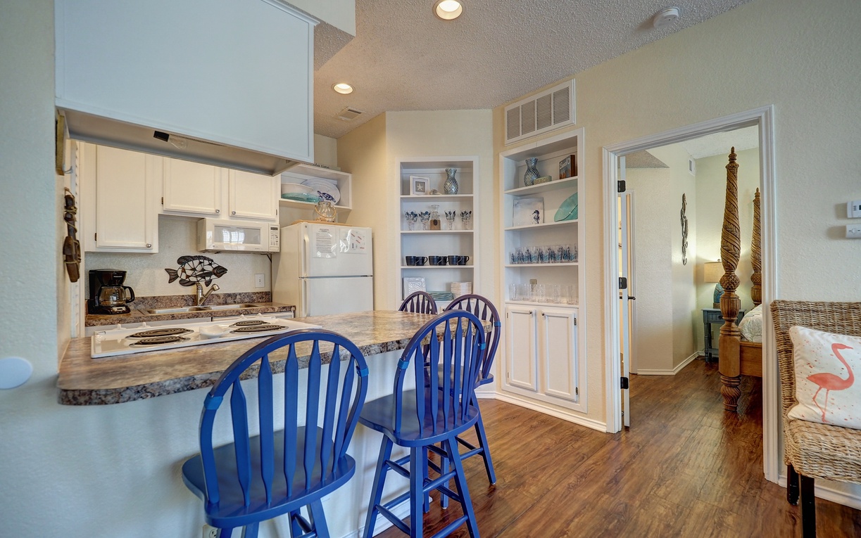 Your bright kitchen flows seamlessly into the living area, complete with a breakfast bar and charming blue Windsor chairs for casual dining.