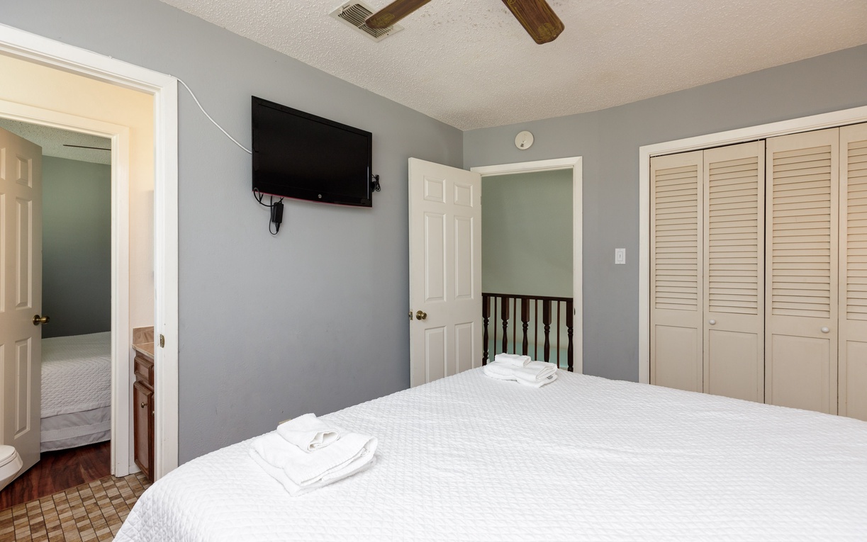 Unwind in your peaceful bedroom featuring a comfy bed, ceiling fan, and wall-mounted TV for relaxing evenings after exploring.