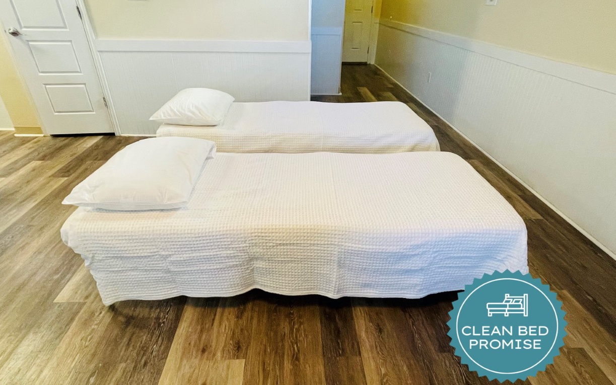 Your comfortable sleeping space features twin beds with crisp white linens on beautiful hardwood floors.