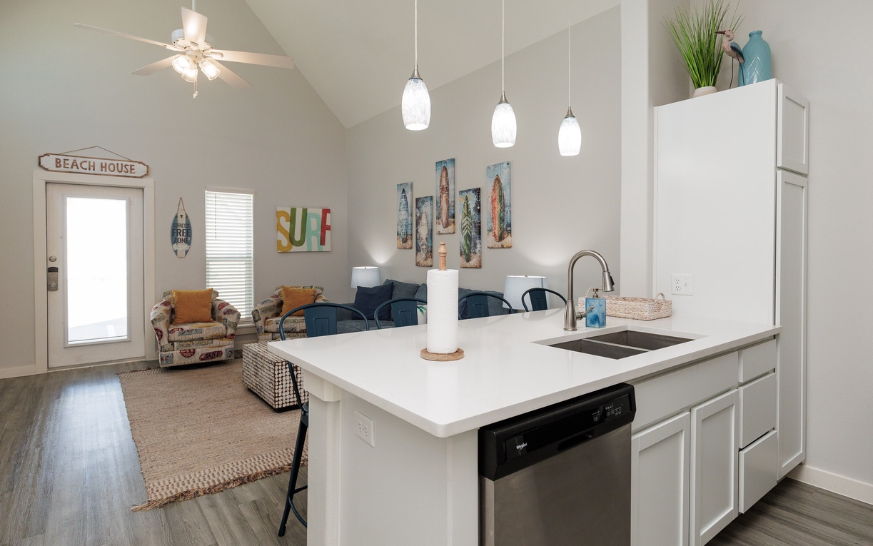 Your bright beach house kitchen opens to a cozy living space where coastal charm meets modern convenience for memorable vacation meals.