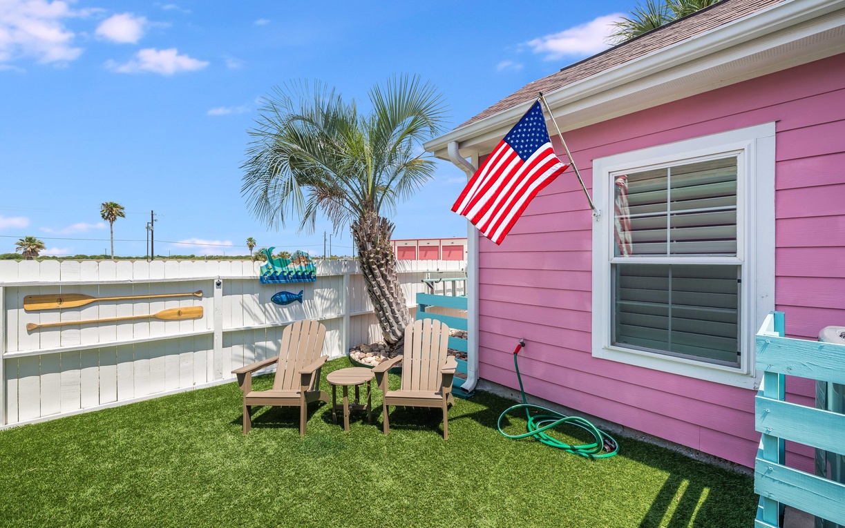 Step into your private tropical oasis with comfy Adirondack chairs where you can unwind under swaying palms in this charming coastal yard.