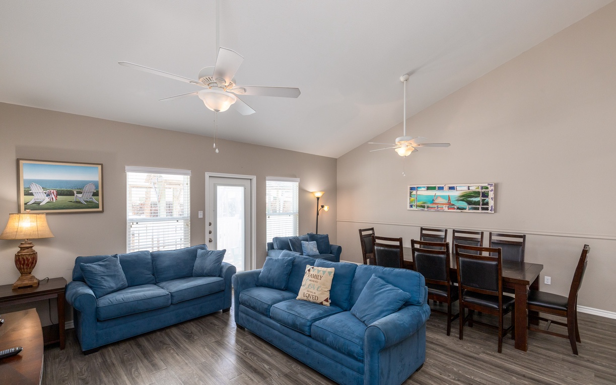 Relax in your spacious living area with plush blue sofas and ceiling fans keeping you comfortable while you plan beach adventures.