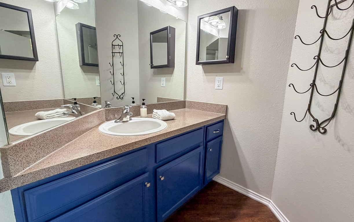 Your spacious dual-sink bathroom offers plenty of room to get ready, with elegant blue cabinetry and modern amenities for a comfortable stay.