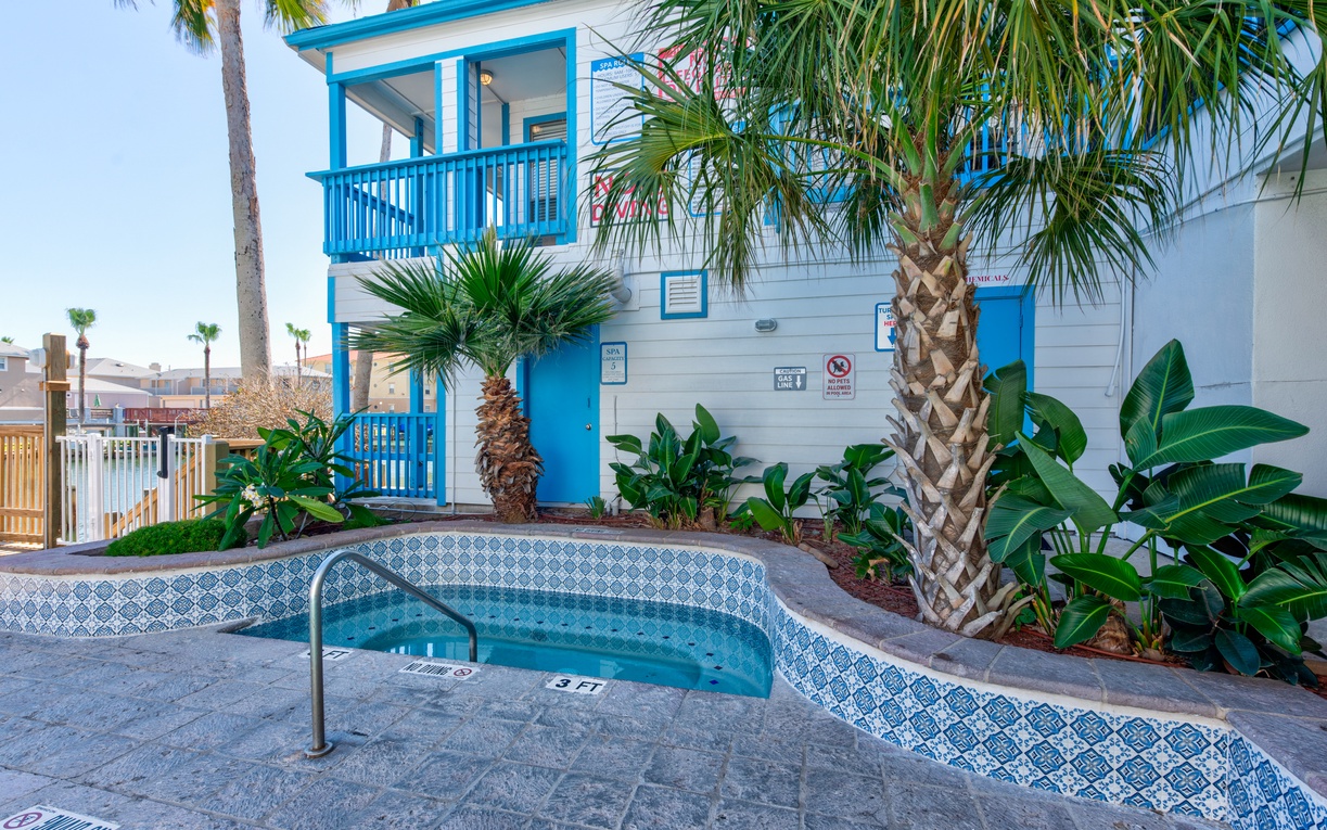 Tropical paradise awaits with a beautifully tiled hot tub surrounded by swaying palm trees and lush landscaping.
