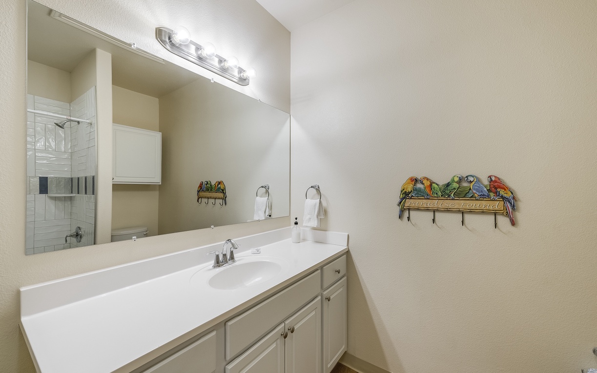 Your bright bathroom features a spacious vanity with ample storage and tropical parrot accents that add playful charm to your daily routine.