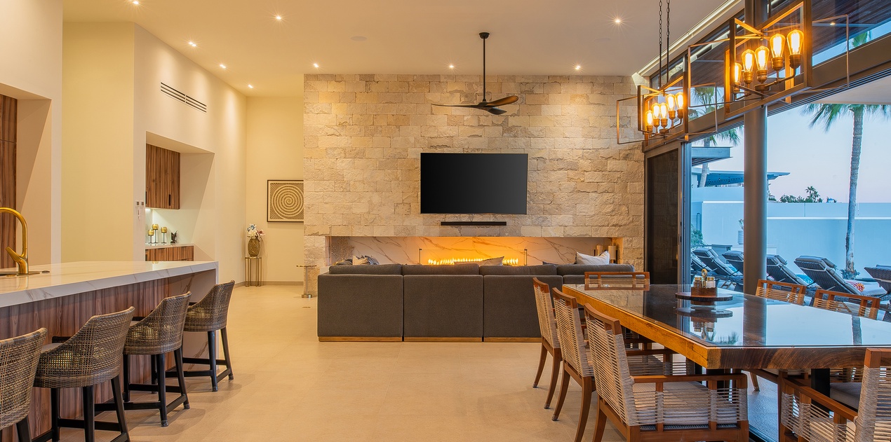 Relax in your elegant open-plan living space with stone fireplace, modern kitchen, and oceanview dining for unforgettable vacation moments.