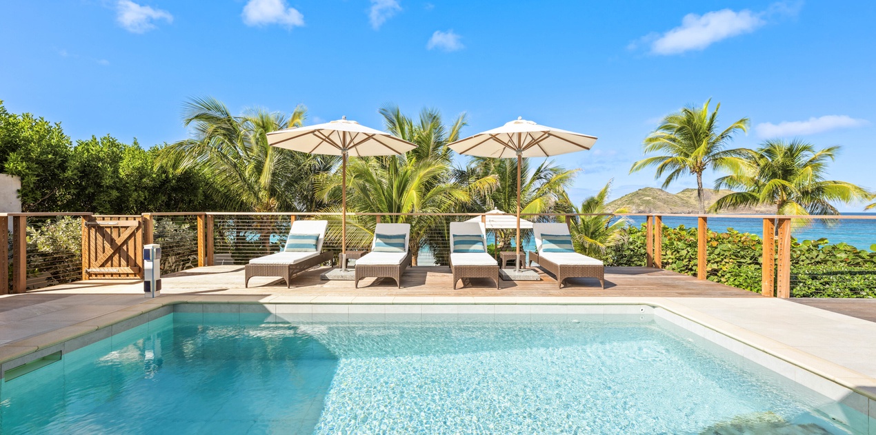 Private pool terrace surrounded by tropical palms with ocean views and comfortable loungers for ultimate relaxation.