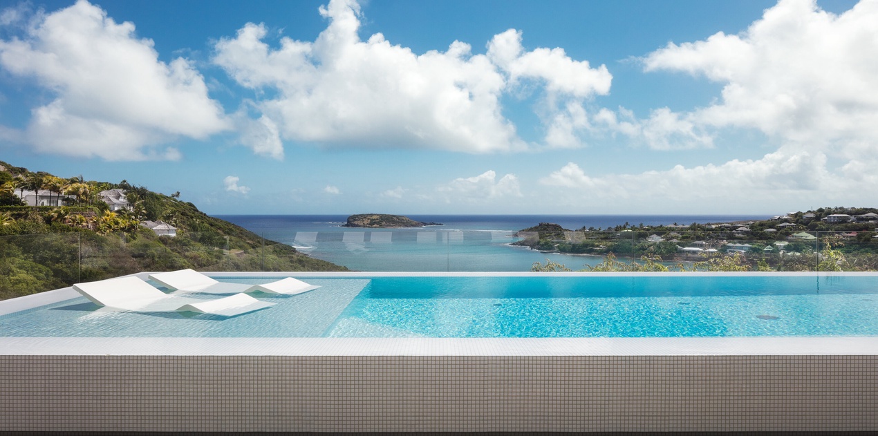 Infinity pool seamlessly blends with turquoise Caribbean waters and dramatic coastline views.
