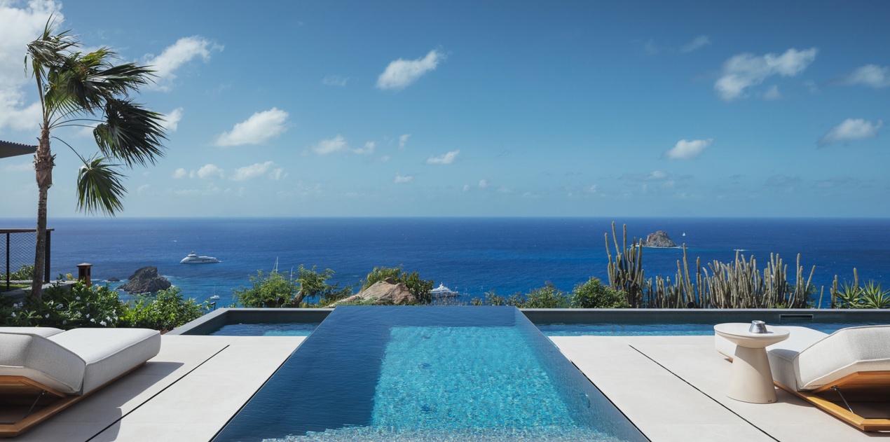 Stunning infinity pool overlooking endless ocean views with tropical landscaping and comfortable lounging areas.