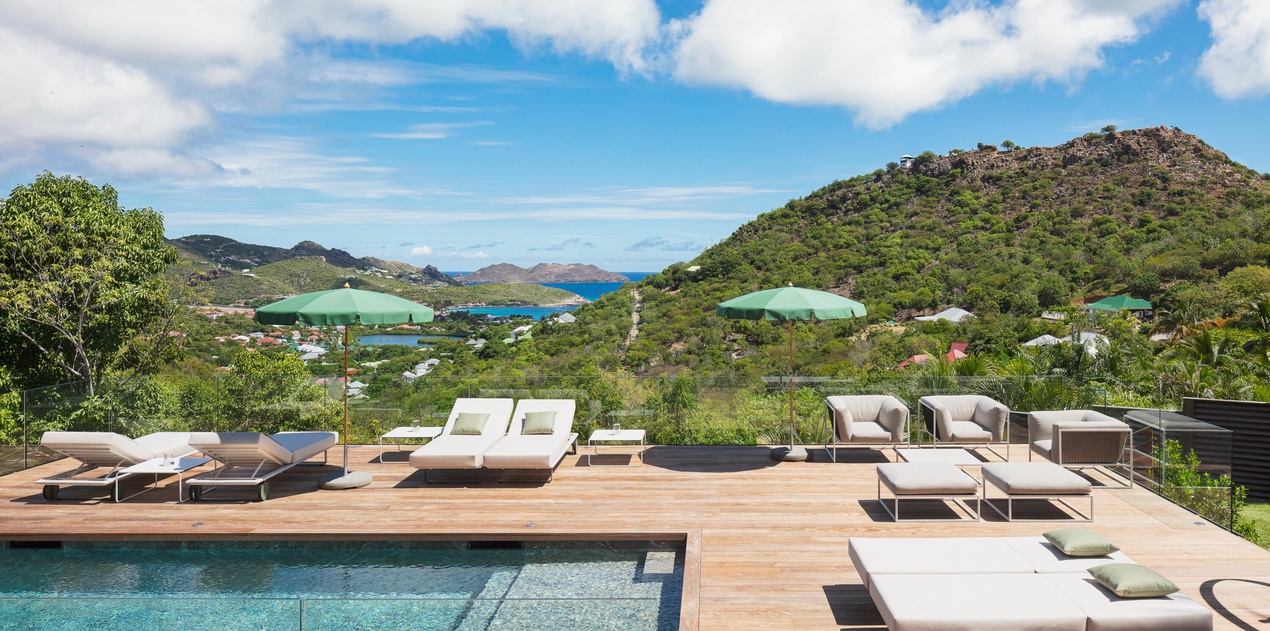 Luxurious infinity pool deck with panoramic ocean and hillside views creates the perfect setting for your Caribbean retreat.