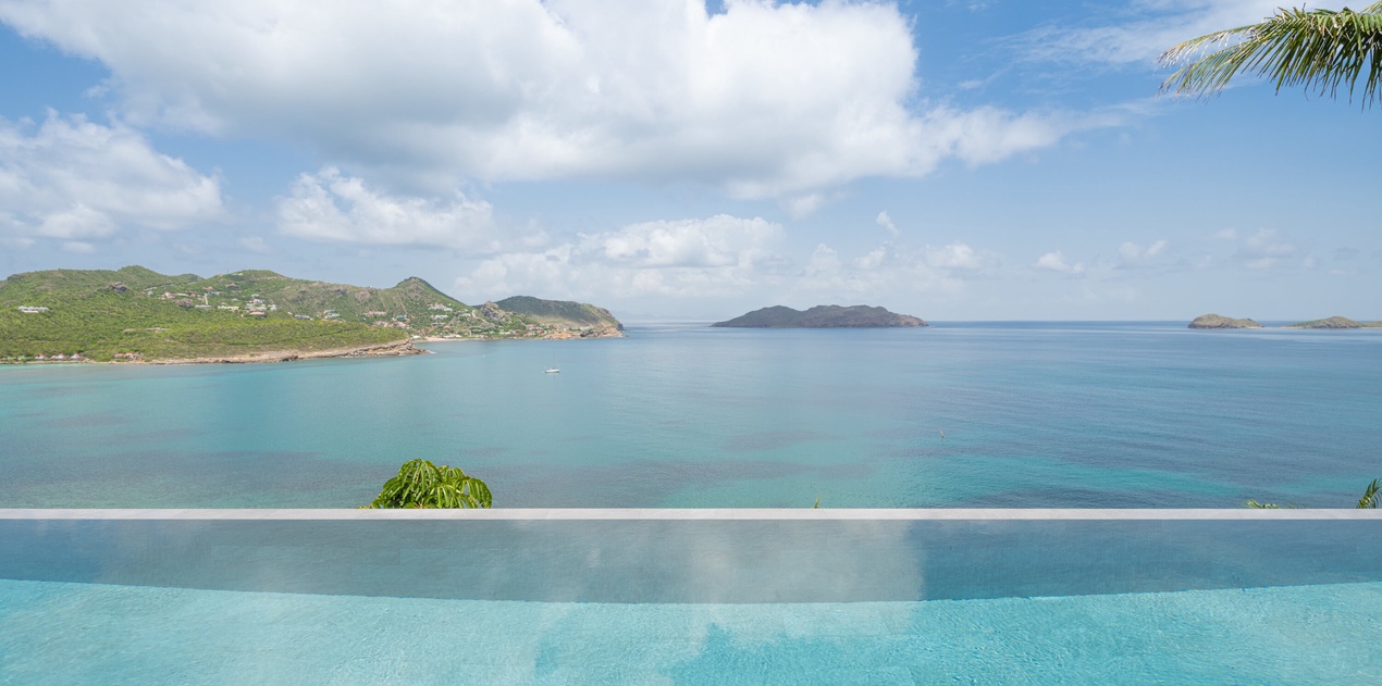 Infinity pool seamlessly blends with turquoise Caribbean waters and tropical islands beyond.
