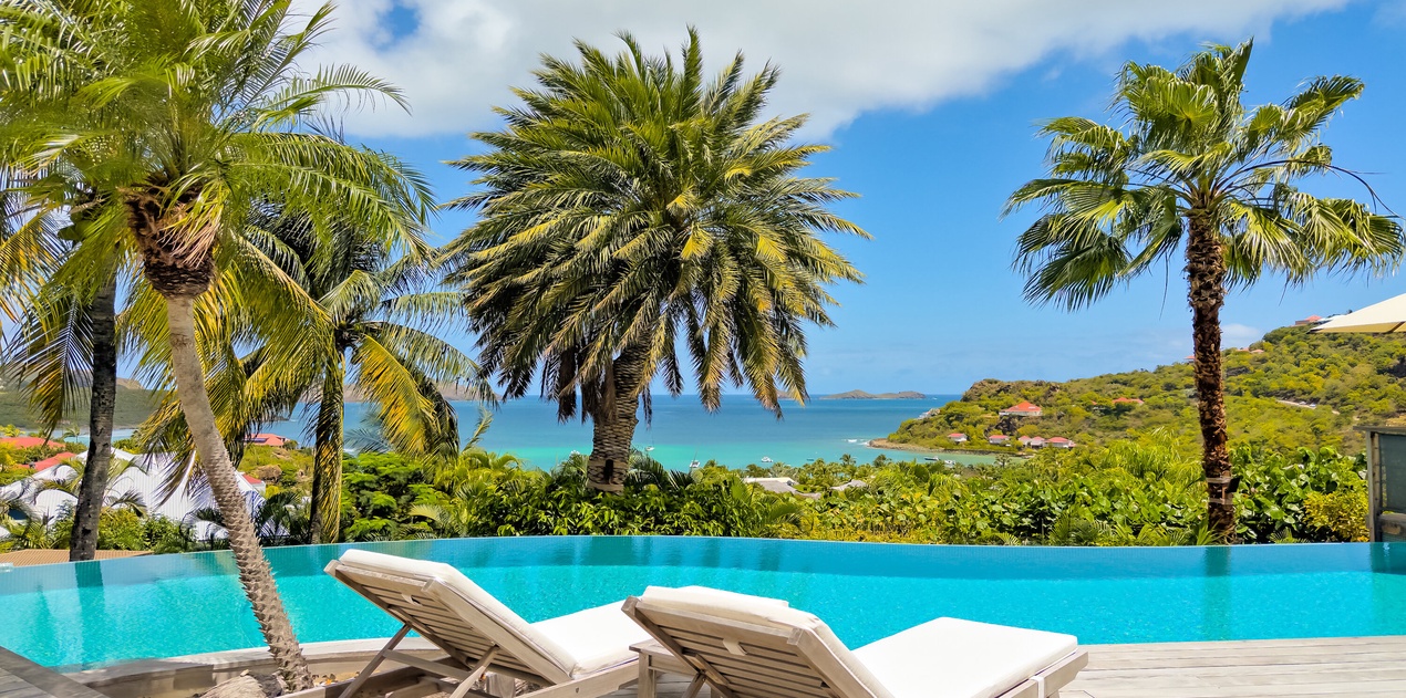 Stretch out on your private sun lounger beside the infinity pool, where turquoise waters blend seamlessly with ocean views and swaying palms frame your tropical escape.