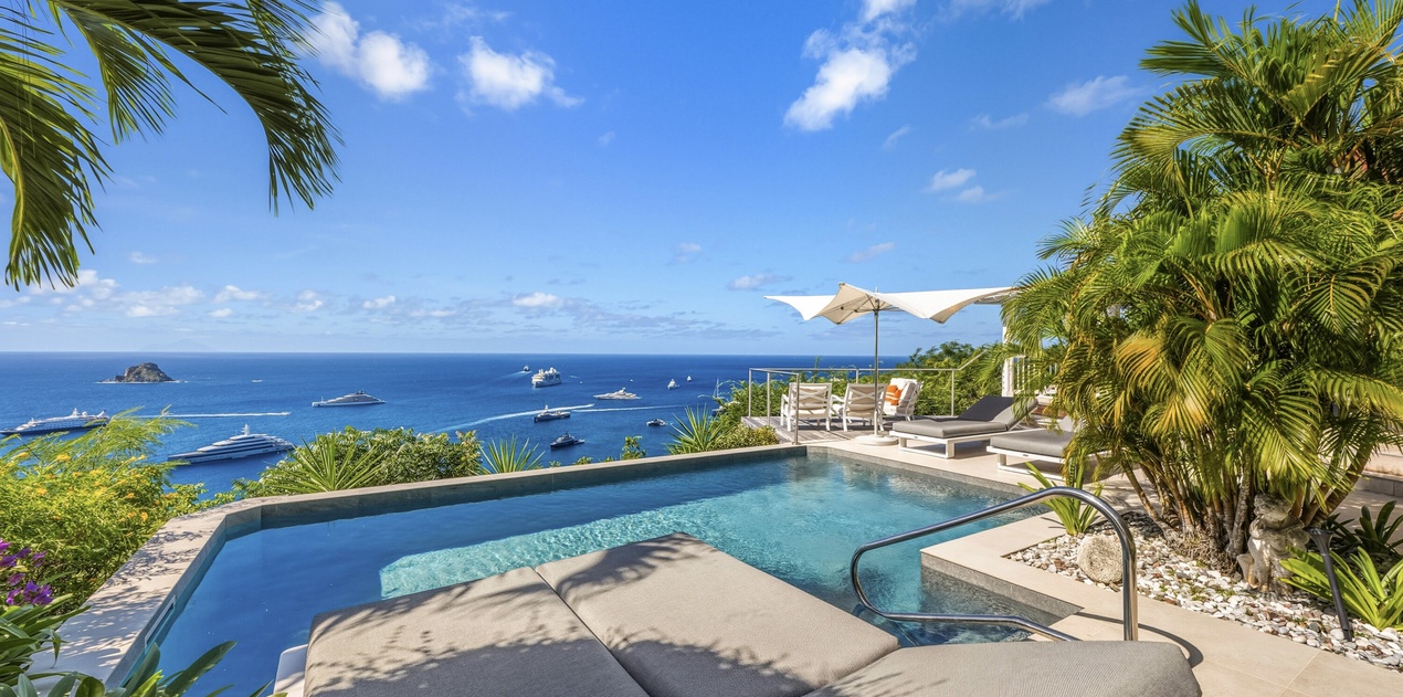 Private infinity pool with panoramic ocean views, tropical palms, and luxury lounging areas create the perfect Caribbean escape.