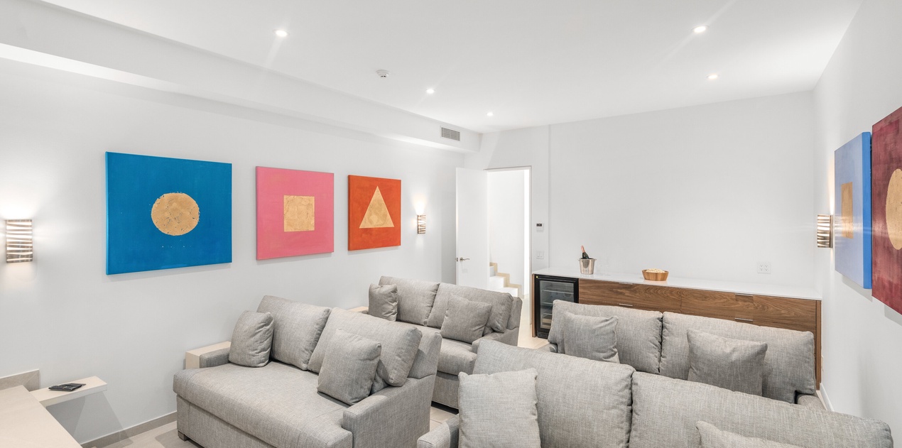 Sink into plush gray sofas surrounded by vibrant geometric art in your spacious, light-filled living area with soaring ceilings.