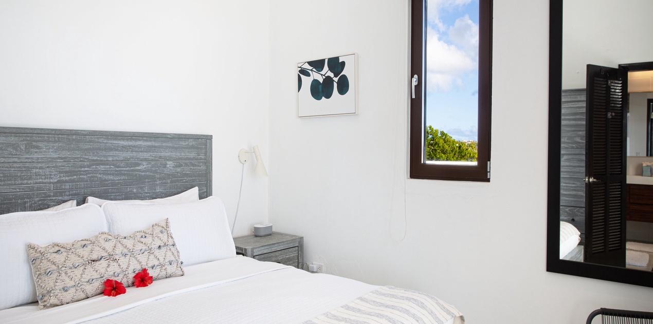 Wake up refreshed in your serene bedroom, where crisp linens and coastal views through the window invite restful mornings and peaceful tropical breezes.