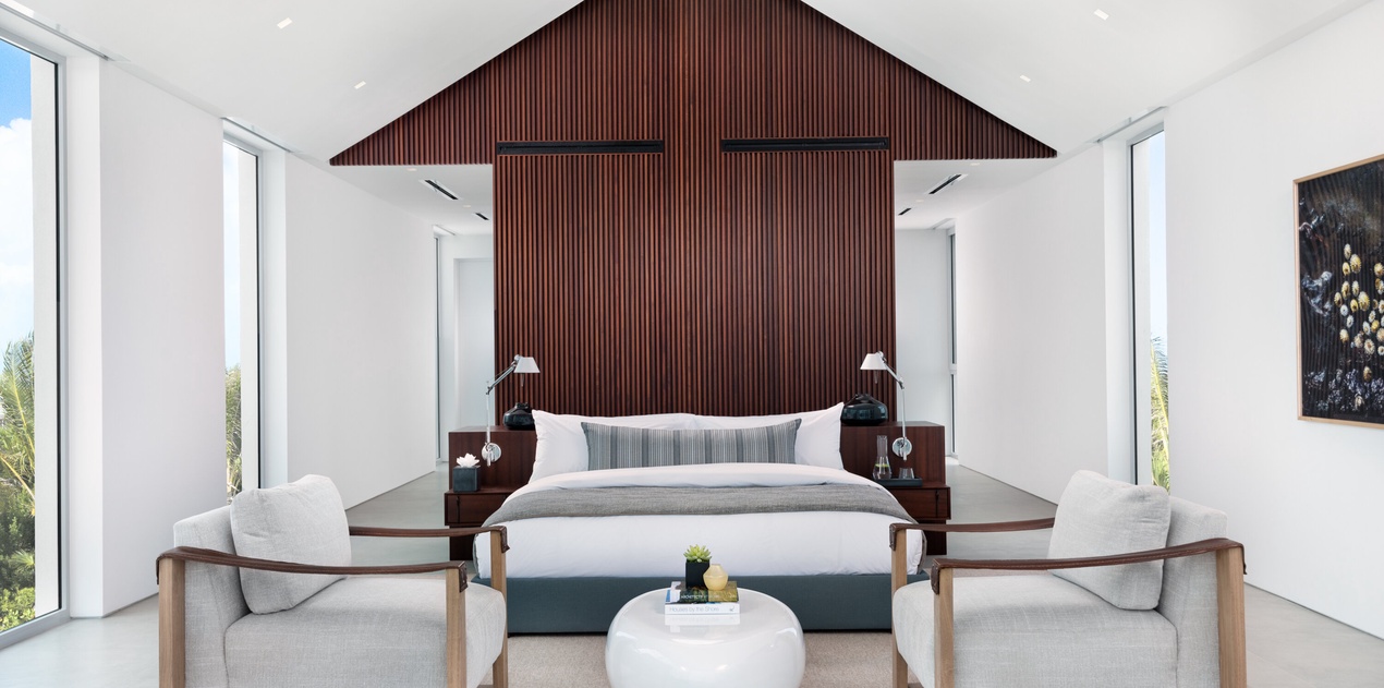 Unwind in your serene sanctuary with floor-to-ceiling windows, contemporary furnishings, and a striking wood accent wall creating the perfect retreat.