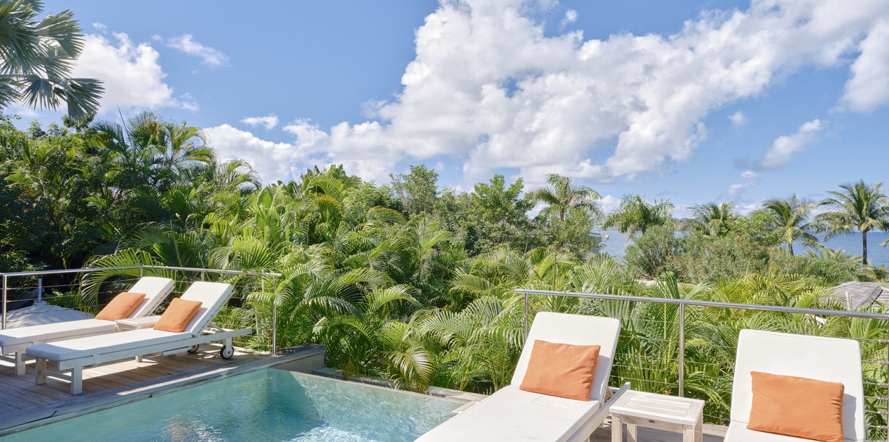 Your private pool terrace offers tranquil lounging with tropical views and orange-accented chairs for ultimate relaxation.