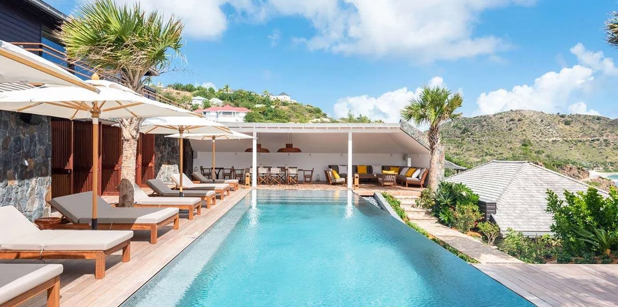 A stunning infinity pool framed by tropical palms and rolling hillsides, offering the perfect place to unwind and soak in the surrounding beauty during your island escape.