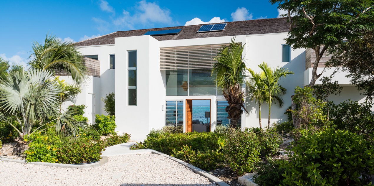 Modern beachfront villa with solar panels and tropical landscaping creates an eco-friendly paradise retreat.