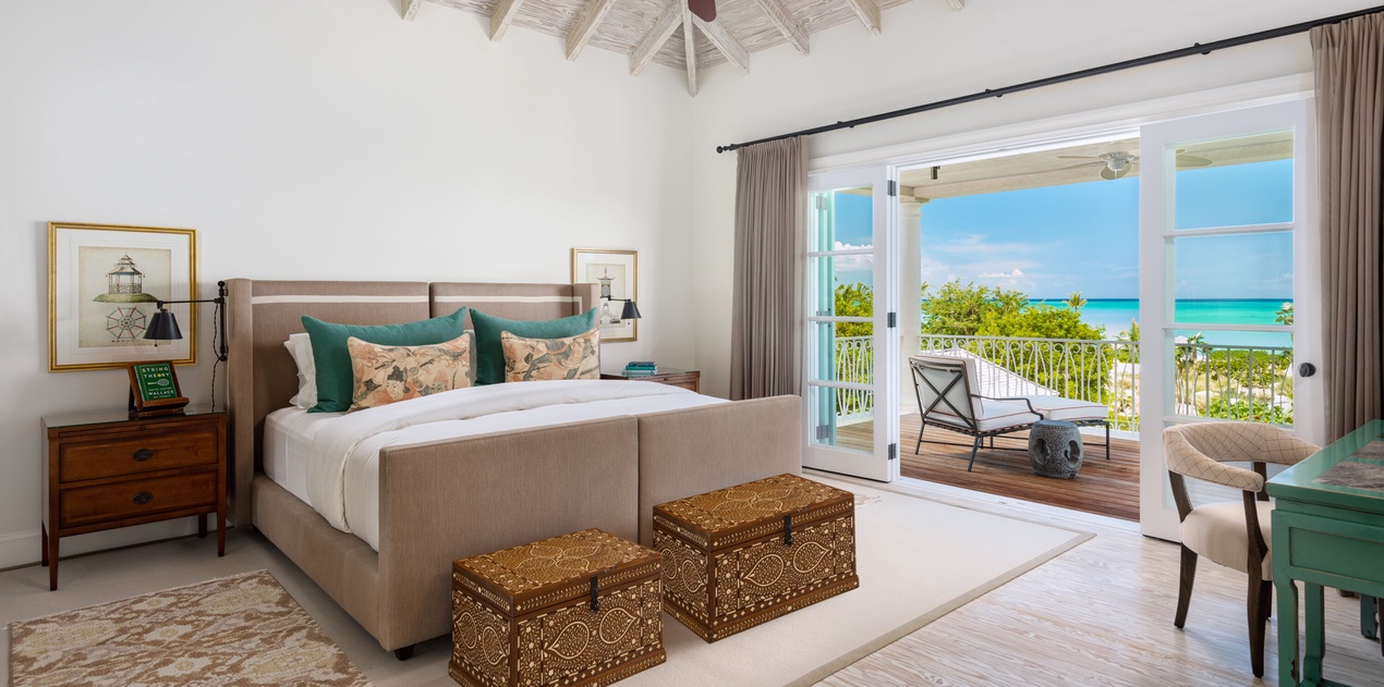 Wake to breathtaking turquoise views through your private balcony doors. This serene bedroom pairs coastal elegance with handcrafted details and airy vaulted ceilings for your perfect island retreat.