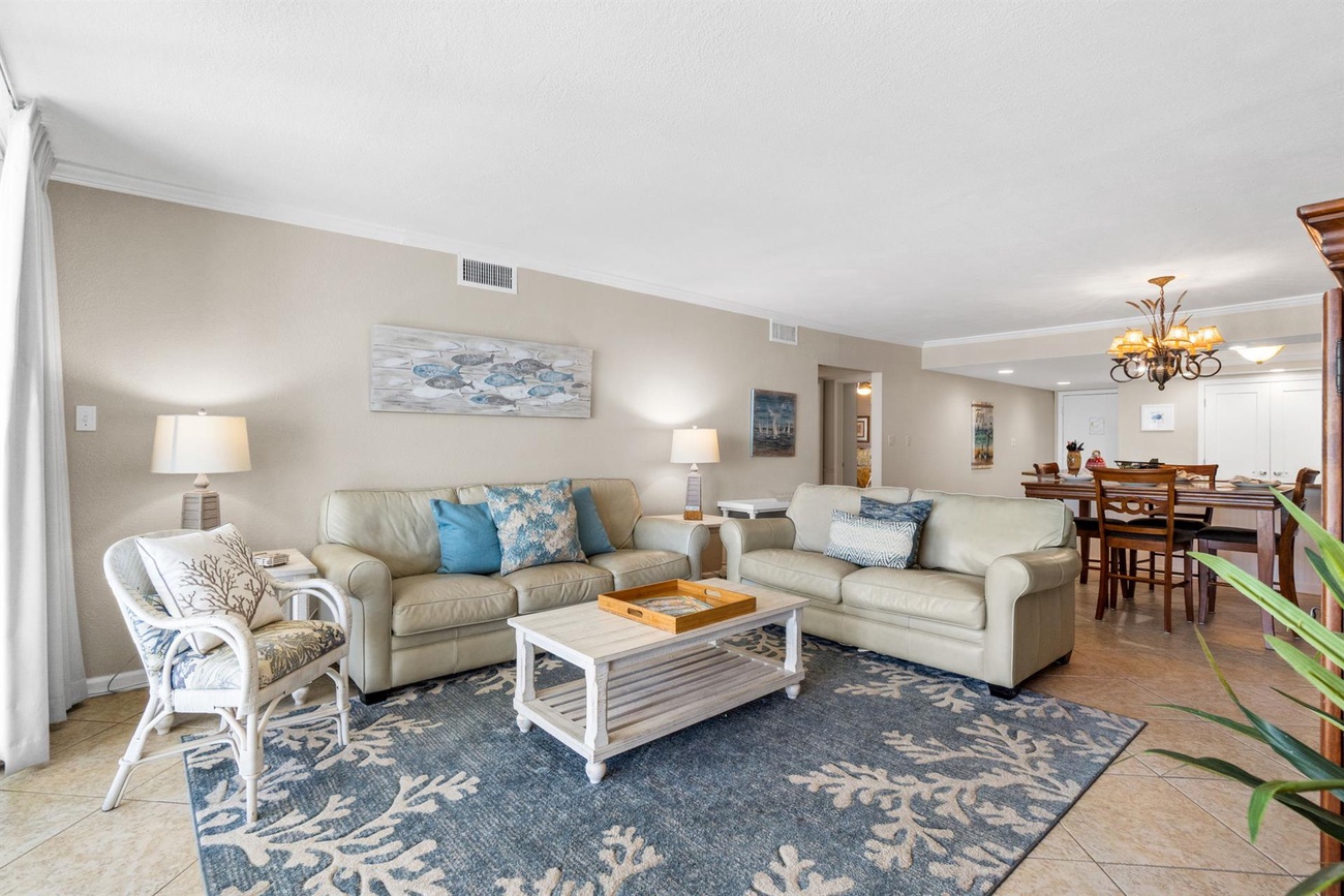 Sink into plush sofas in your spacious living room, where coastal blues and whites create a serene atmosphere for relaxing after beach adventures.