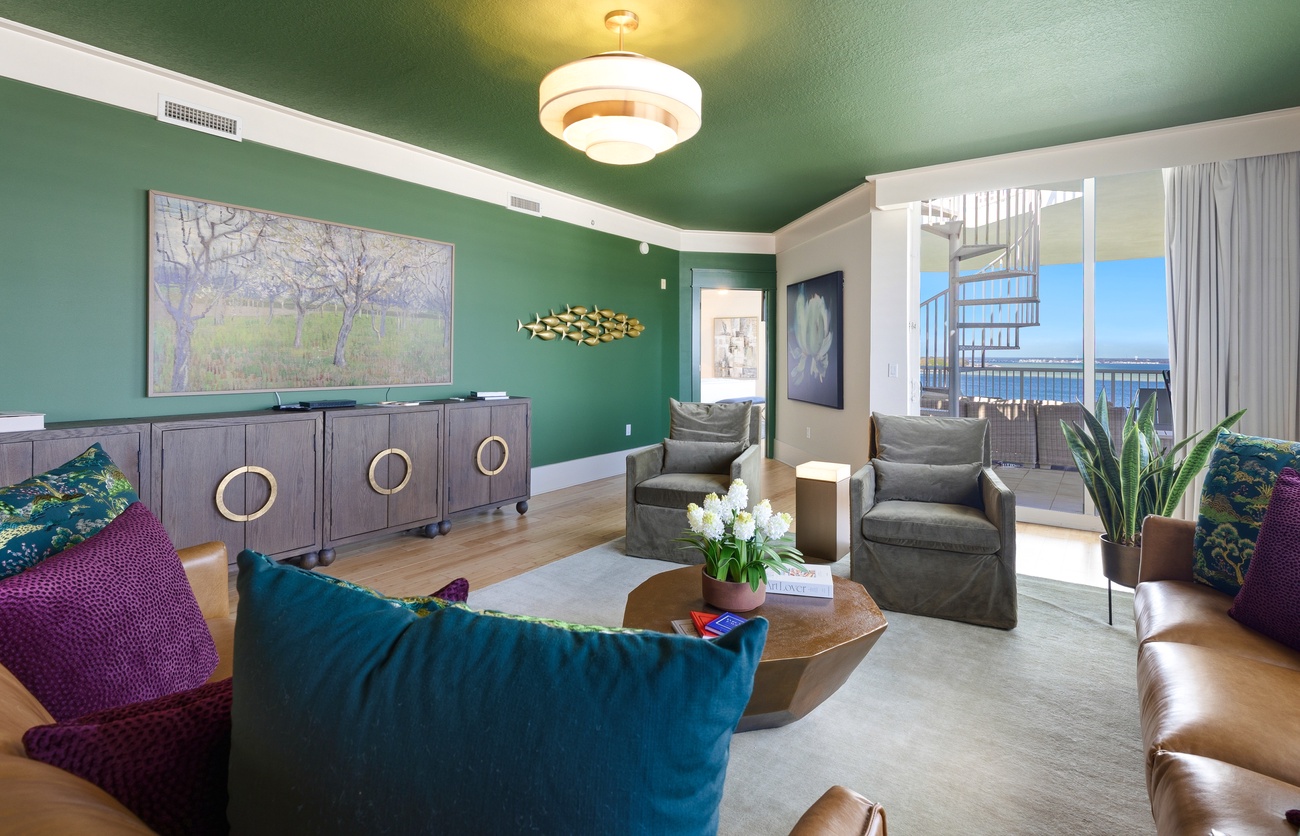 Sink into plush seating in your stylish living space, where emerald walls and ocean views create the perfect backdrop for relaxation.