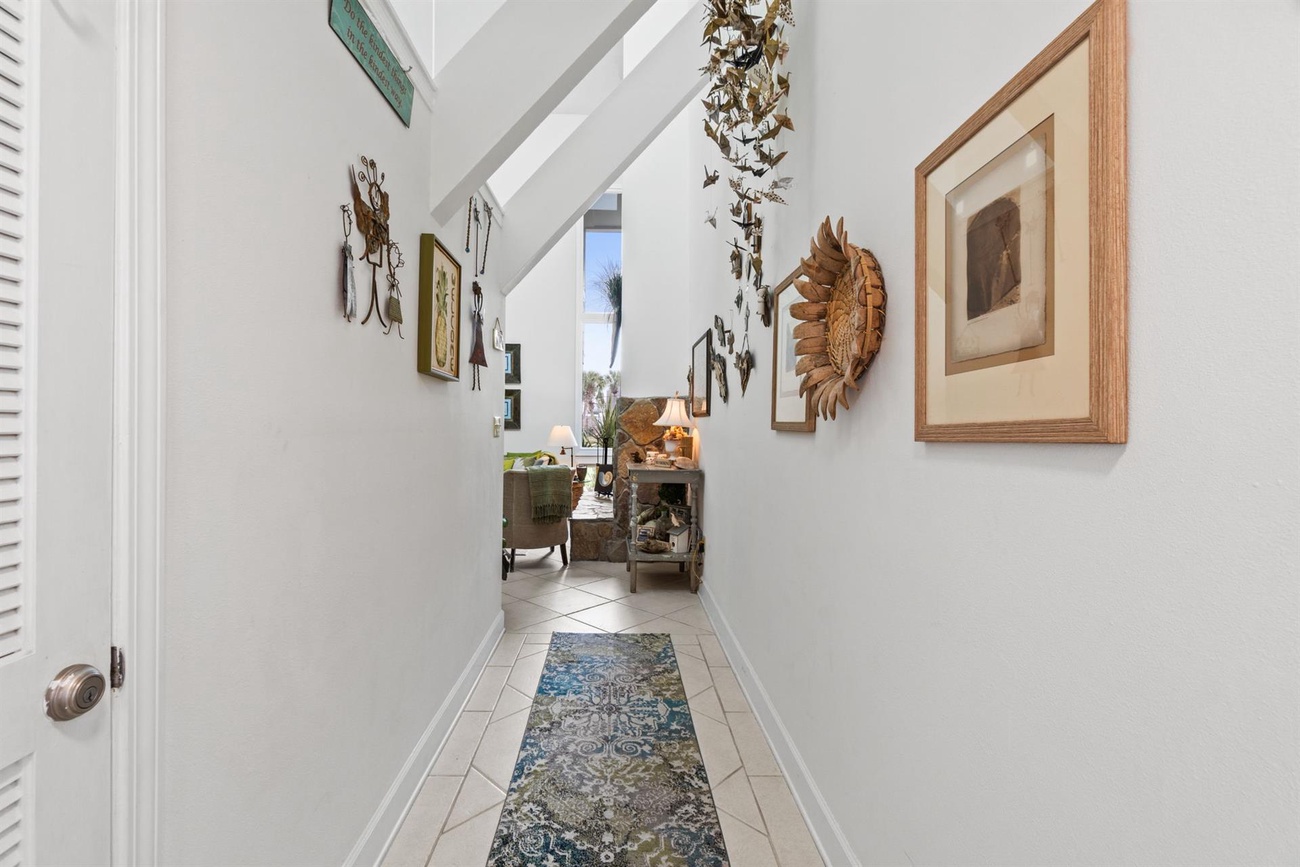 Step into your bright hallway adorned with curated artwork and tropical accents, leading you to comfortable living spaces filled with character.