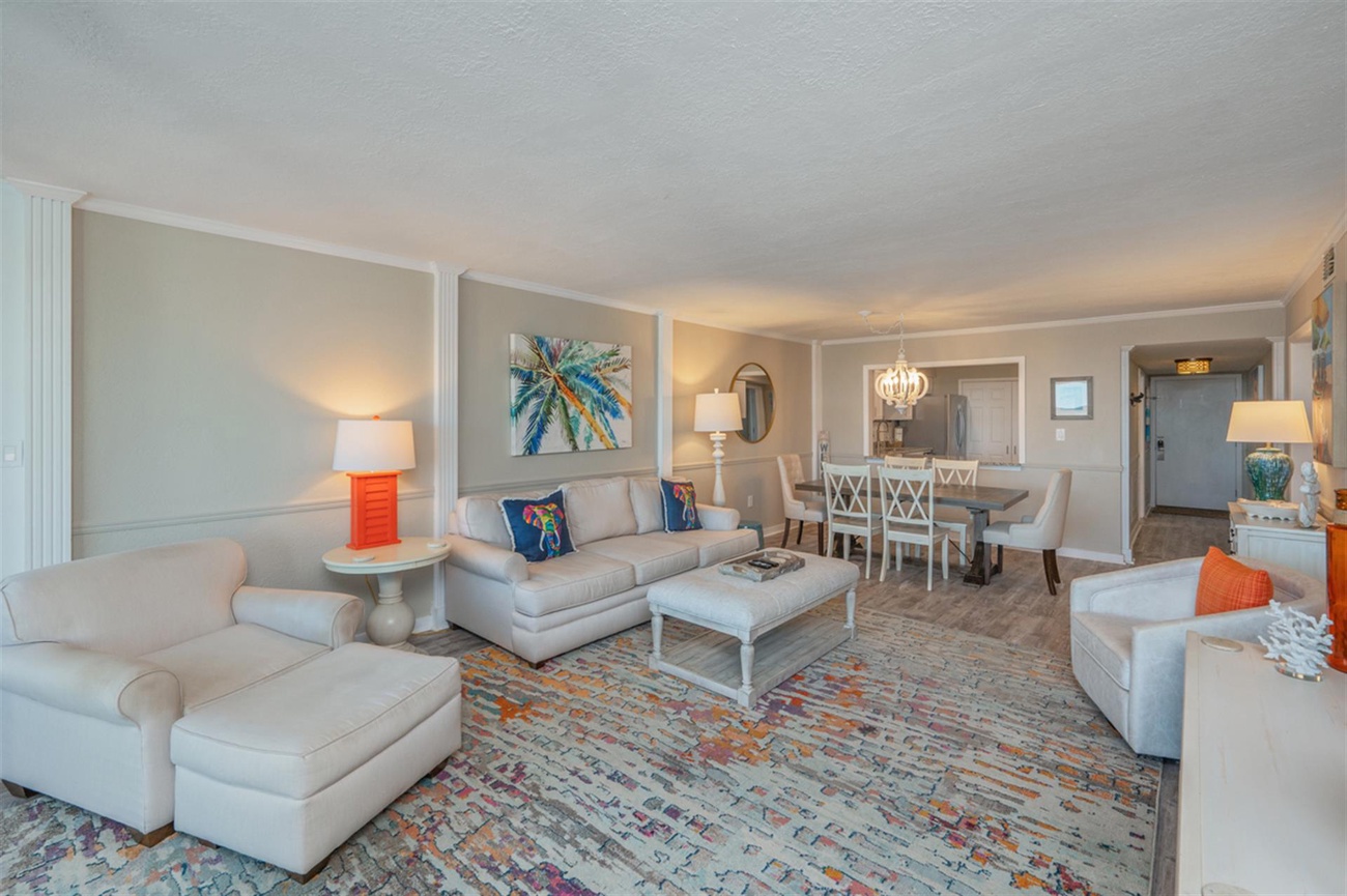 Sink into plush sofas and unwind in your spacious living room, where coastal artwork and pops of coral create a serene retreat.