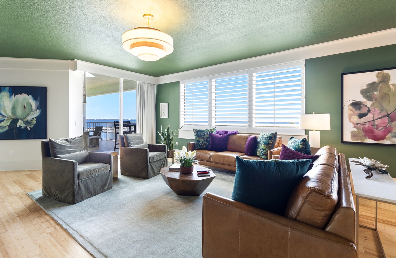 Sink into plush leather seating while ocean views fill your windows in this stylish living space with vibrant art and warm lighting.
