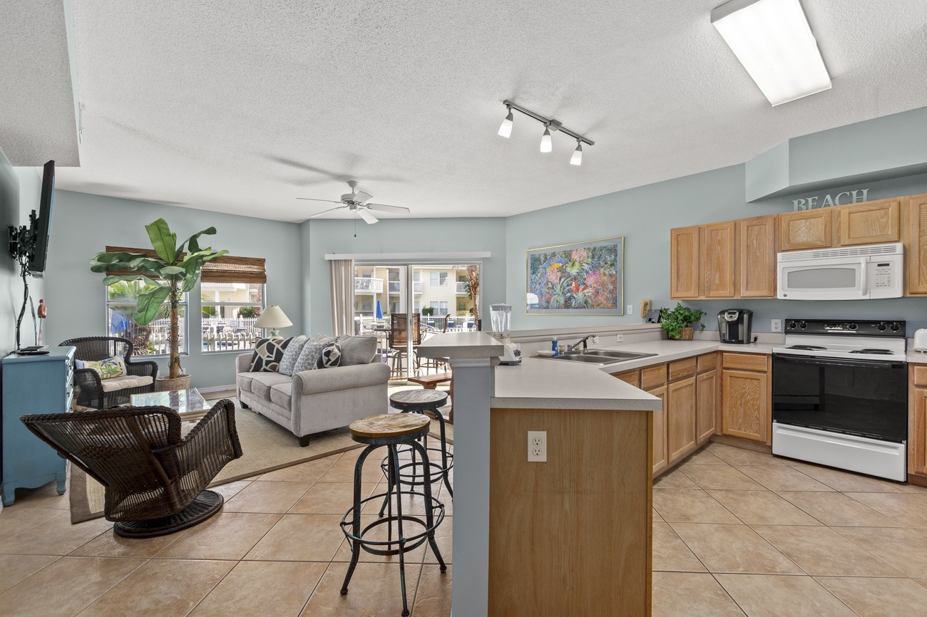Your spacious open-concept living awaits, where coastal blue walls meet warm wood accents and natural light floods through the skylight above.