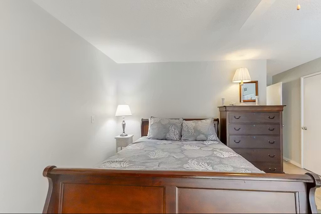 Drift into peaceful sleep in this serene bedroom with its elegant wooden furnishings and soft gray linens creating your perfect retreat.