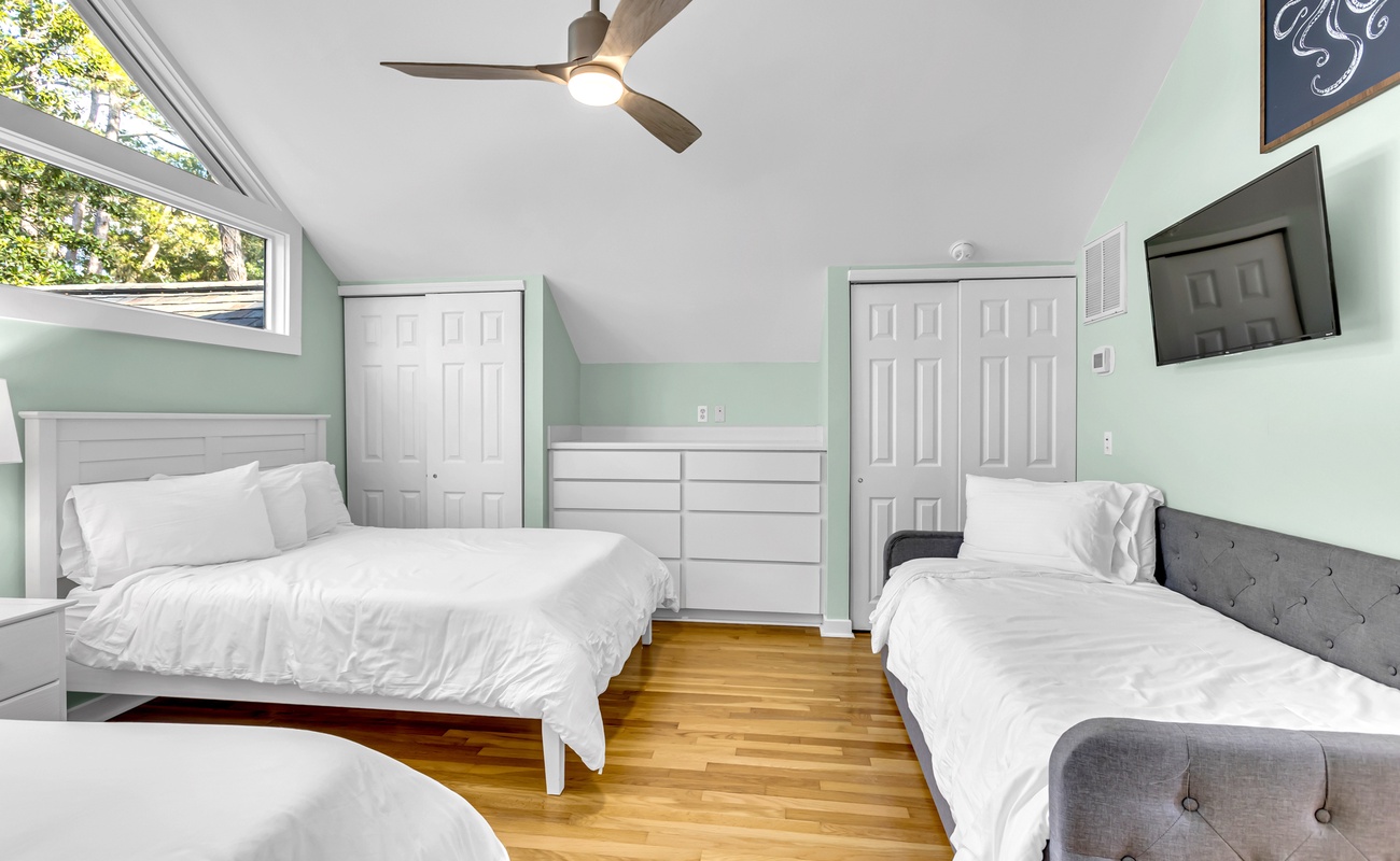 Rest peacefully in your spacious bedroom with crisp linens, natural light, and climate comfort from the ceiling fan above.