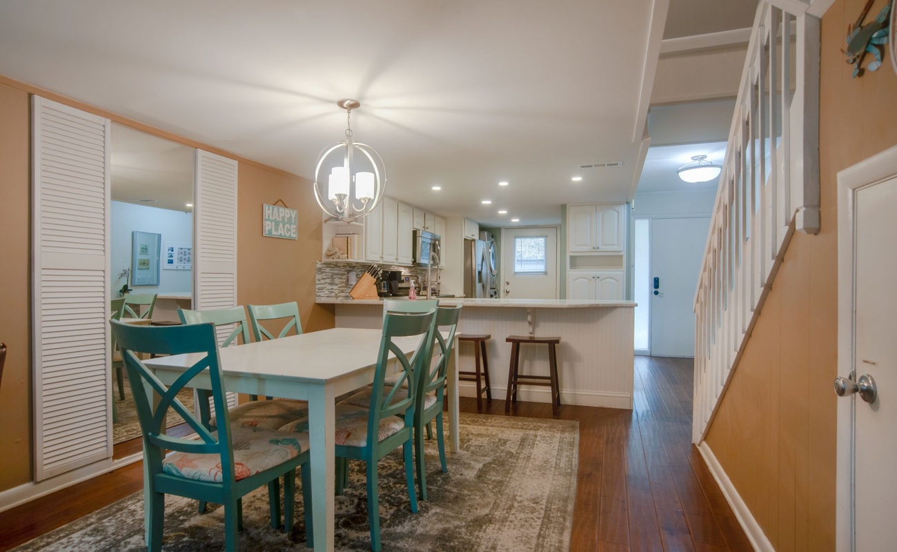 Your bright dining space flows seamlessly into the kitchen, where turquoise chairs add coastal charm to family meals together.