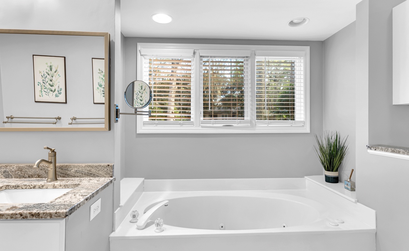 Unwind in your spa-like bathroom featuring a deep soaking tub, granite vanity, and natural light from plantation shutters.