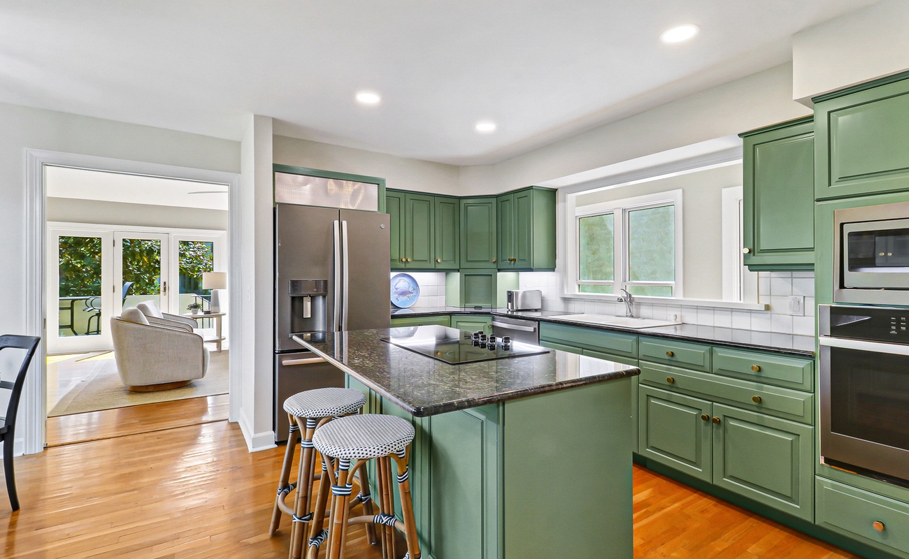 Your spacious kitchen features stunning sage-green cabinets, granite countertops, and modern stainless steel appliances - perfect for creating memorable meals together.