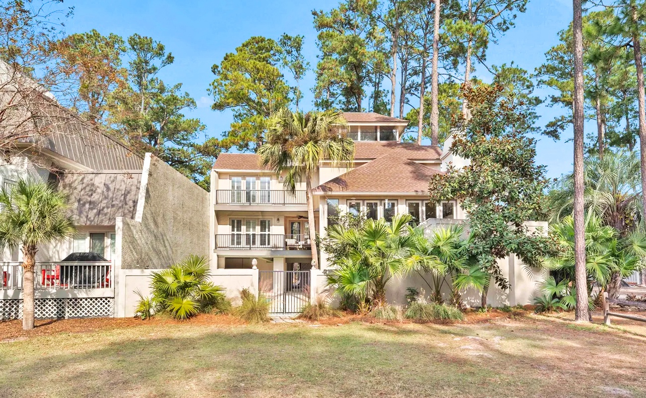 Charming multi-story vacation home nestled among towering pines and lush palms in a peaceful residential setting.