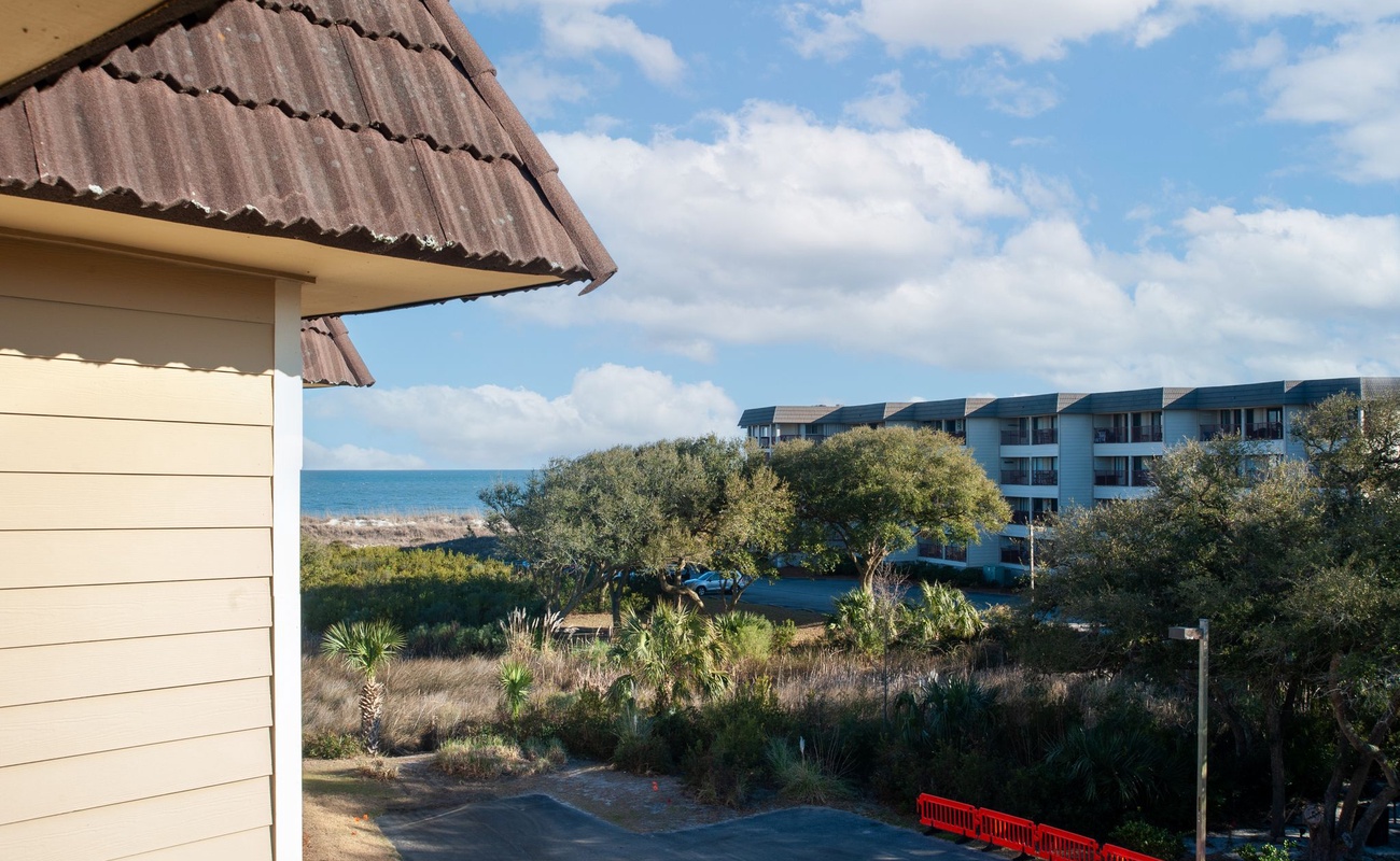 Beachfront property offers stunning ocean views with nearby resort buildings nestled among lush coastal vegetation and tropical landscaping.