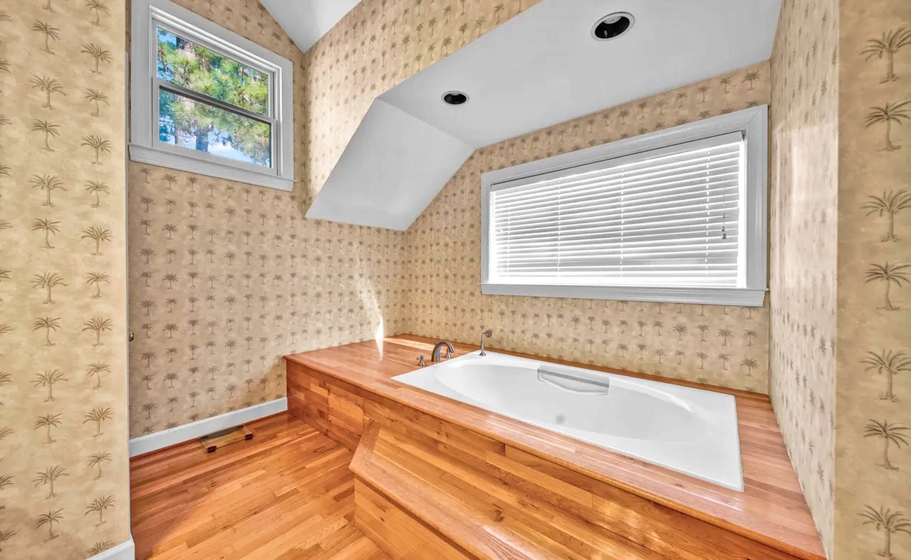 Soak in your private tub surrounded by tropical palm wallpaper and rich wood floors for the ultimate relaxing retreat.