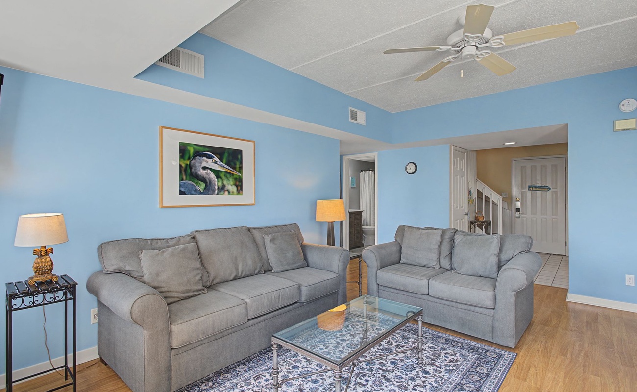 Unwind in your bright living space with plush gray sofas and cheerful blue walls that create a coastal feel.