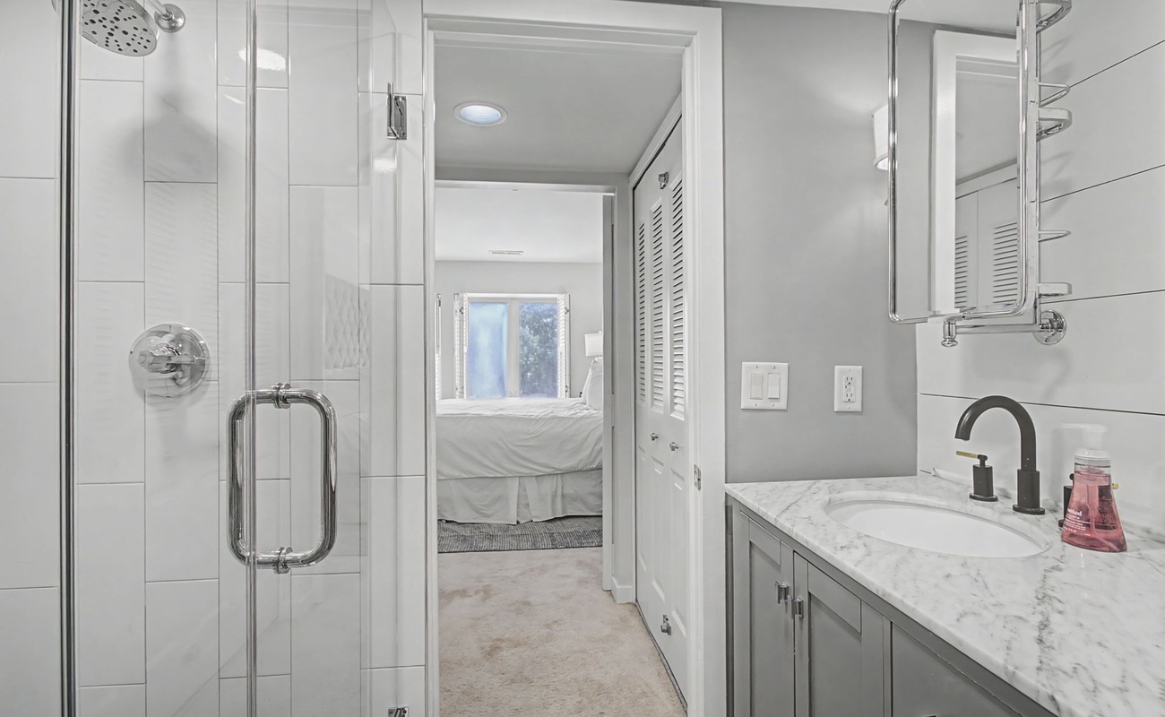 Pamper yourself in this spa-like bathroom with its luxurious marble countertops, spacious glass-enclosed shower, and elegant modern finishes.