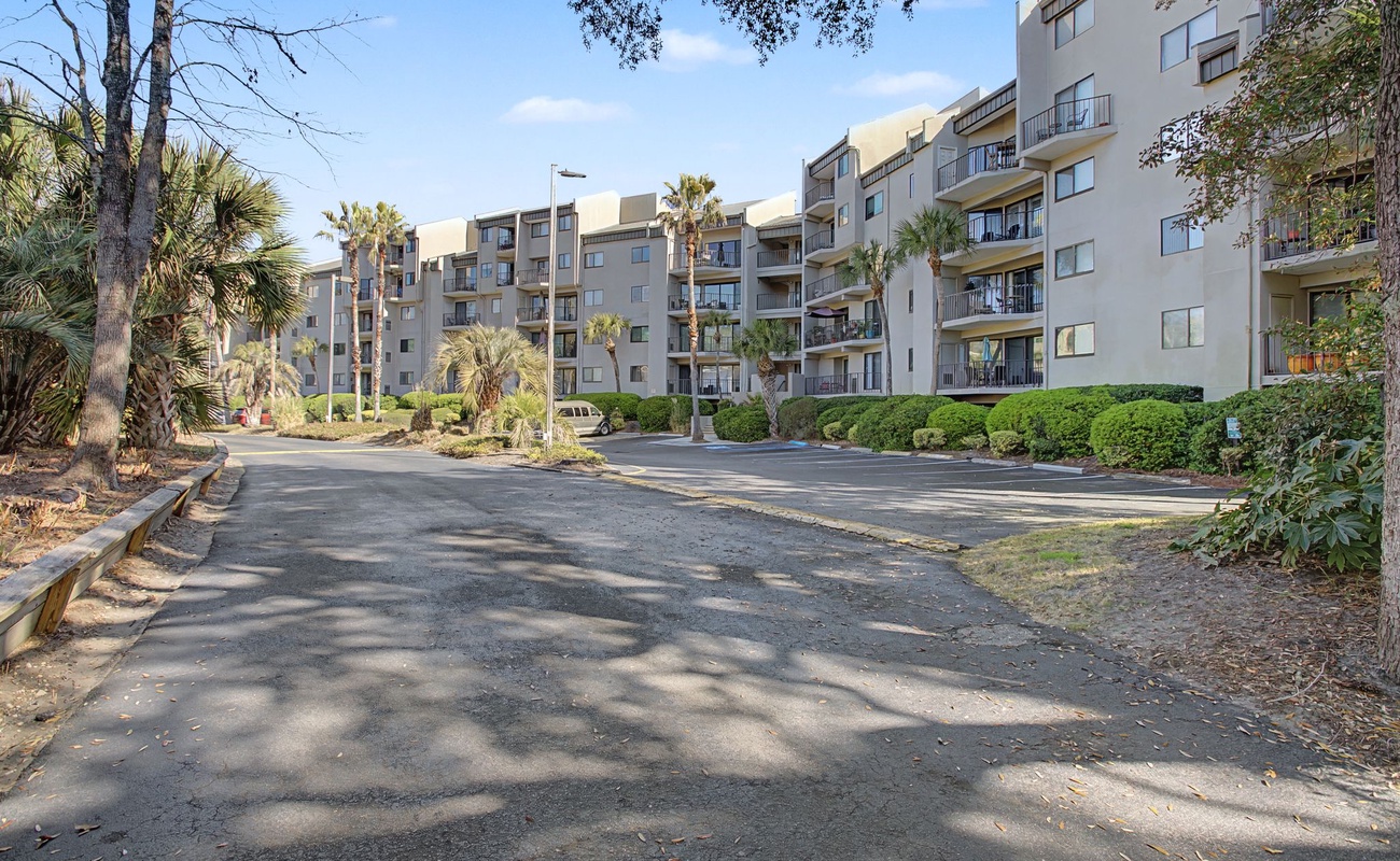 Modern multi-story vacation rental complex surrounded by lush tropical landscaping and mature palm trees with convenient on-site parking.